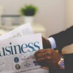 Close-up of a businessman reading a newspaper indoors, focusing on business headlines.